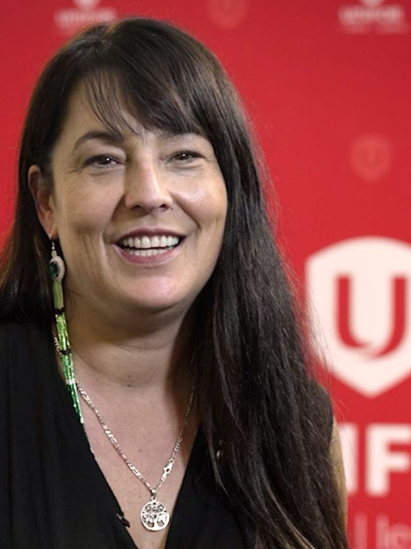 An indigenous women smiling in front of a red Unifor backdrop